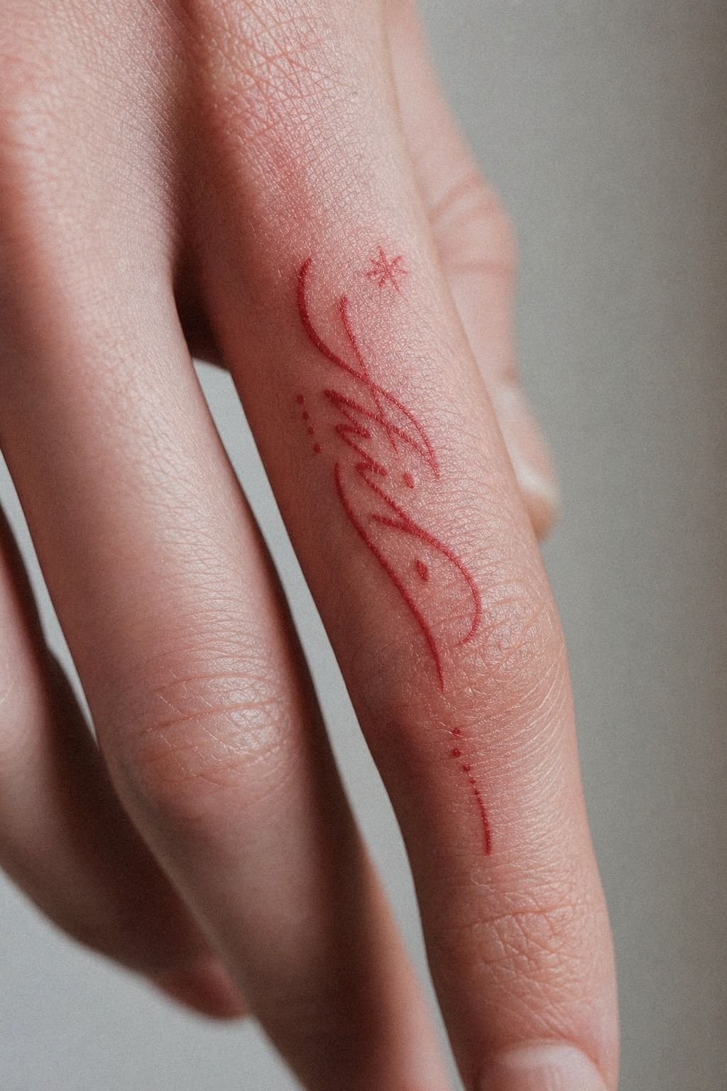 Red Ink Name Finger Tattoo