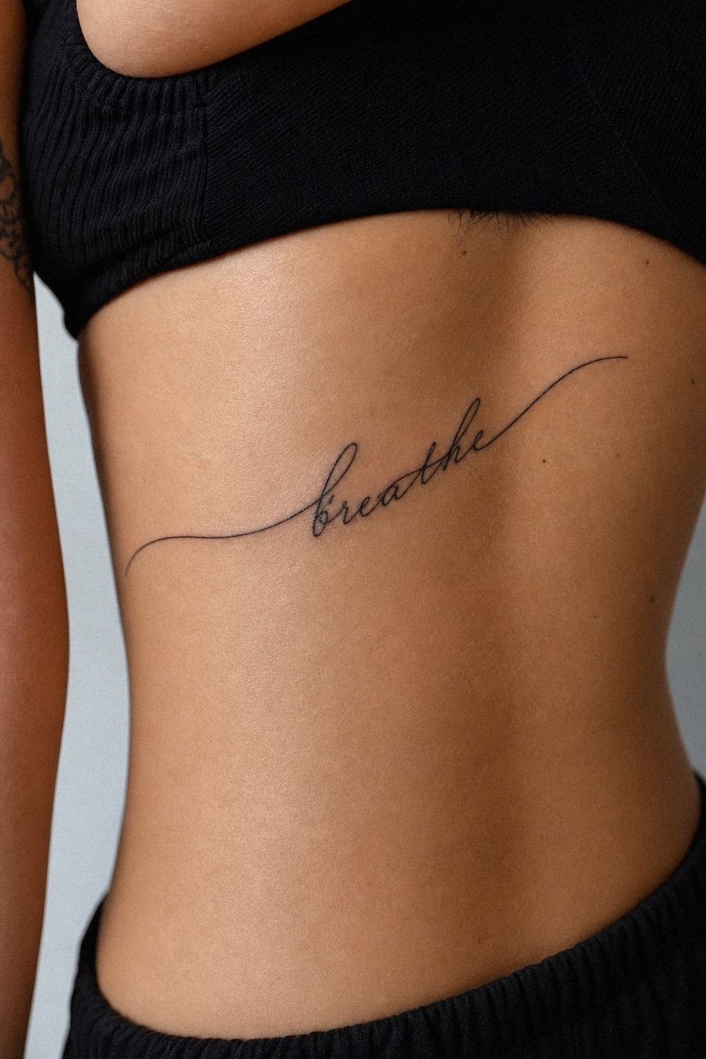 Single Word Rib Tattoo With Quiet Meaning